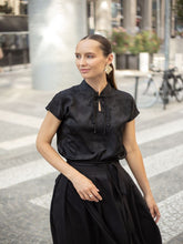 A woman wears a black ruched dress